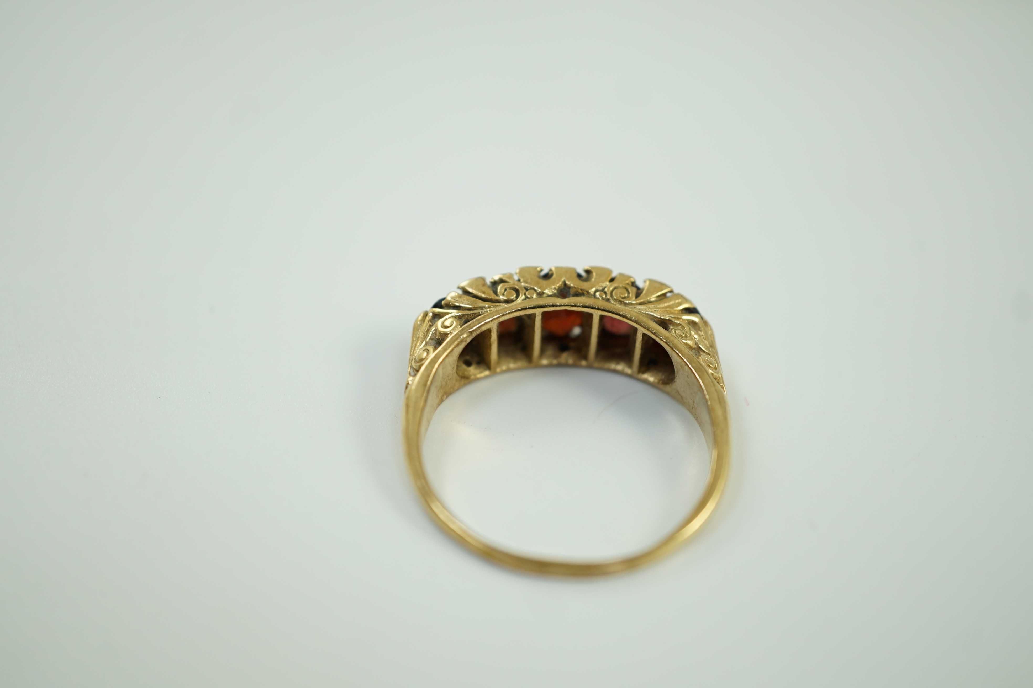 A 1960's Victorian style 9ct gold and graduated five stone garnet set half hoop ring, with diamond chip spacers, size V, gross weight 6 grams.